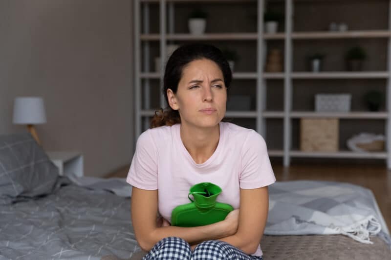 Dysmenorrhea.,Tired,Sad,Young,Latin,Lady,Crouch,On,Bed,Alone